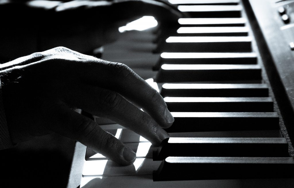 black and white photo of hands playing piano, practicing