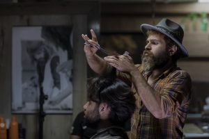a rustic image of a bearded barber, with a blurred, brown hipster setting in the background, symbolising innovation and entrepreneurship in opening up a small local business