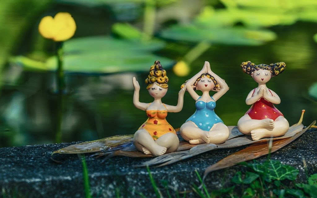 three plastic toy barbie dolls doing 'yoga'