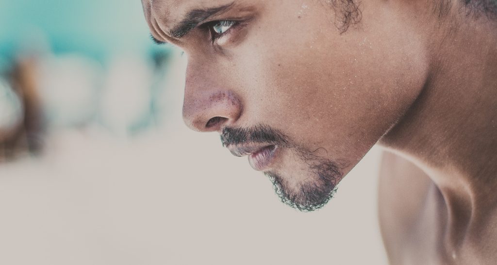 young man with facial hair looking forward - focused on whatever task is at head. looking forward as if about to go for a run. Symbolising focus in business and looking ahead 