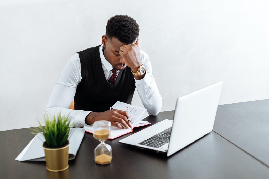 man sitting at his desk on his laptop looking stressed - in business