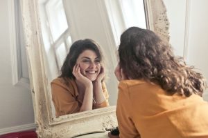 woman looking in the mirror smiling, symbolising confidence