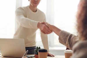 two business people shaking hands, representing a successful meeting about pay
