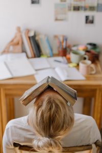picture of woman with book on head - tired and stressed with critical / destructive thoughts