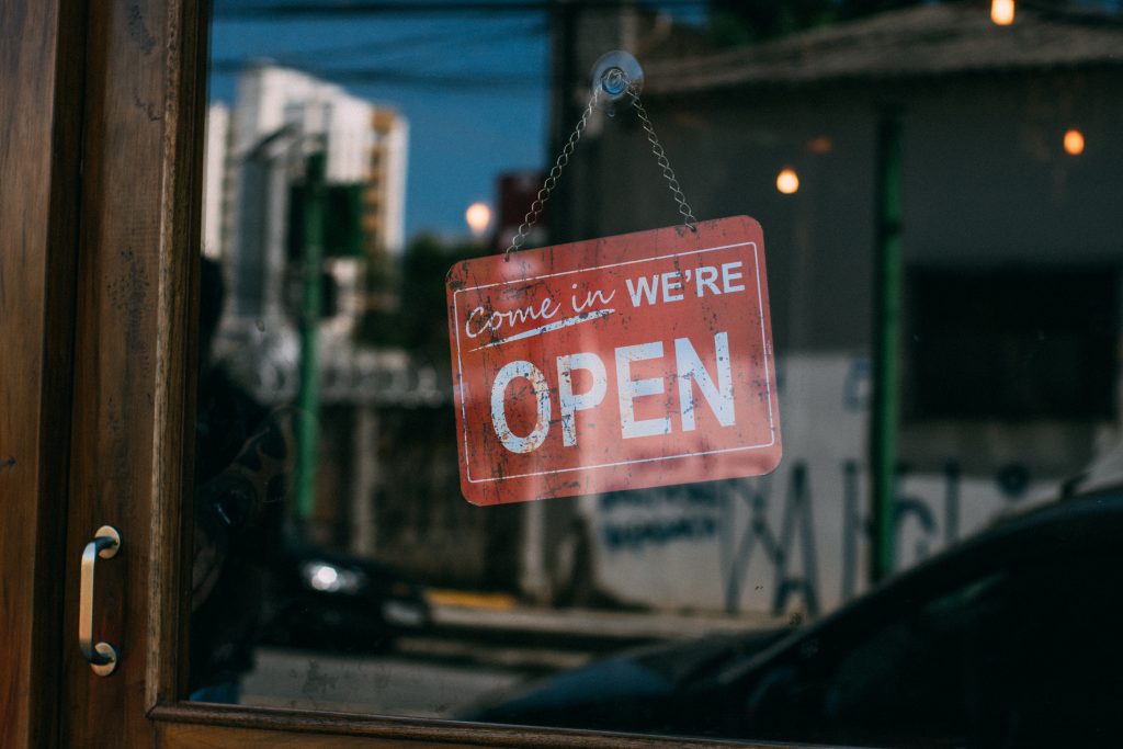 image of a shop front saying "come in we're open" - business owner, example of an entrepreneurial pursuit 