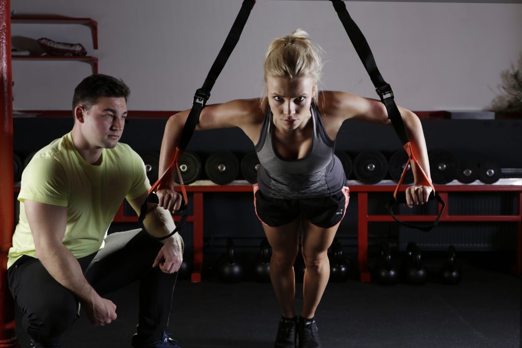 man working as a coach in a gym training a woman 