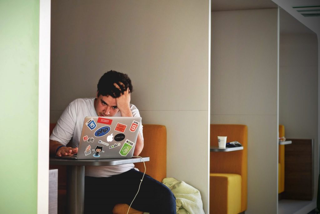 man sitting at laptop looking stressed - marketing online can be stressful 