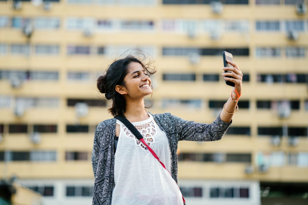 Woman holding up phone to represent positive mindset and beliefs