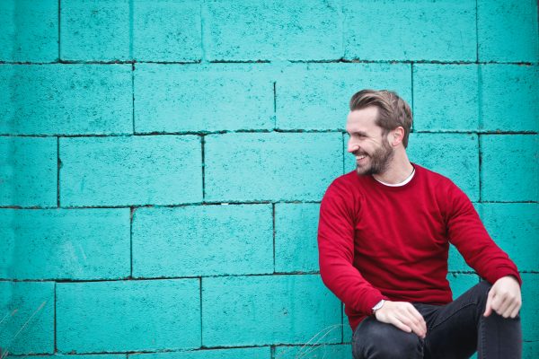 Male entrepreneur sitting against blue wall, high emotional intelligence